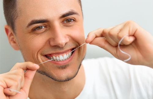 man smiling and flossing his teeth 