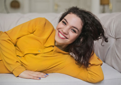 young woman lounging on couch with Marco Island cosmetic injectables.