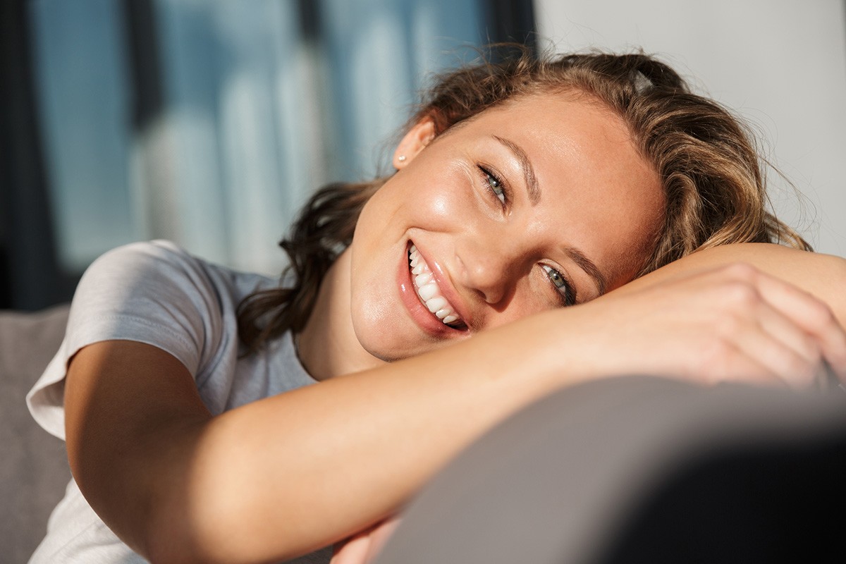 young woman lounging on couch with Marco Island cosmetic injectables.